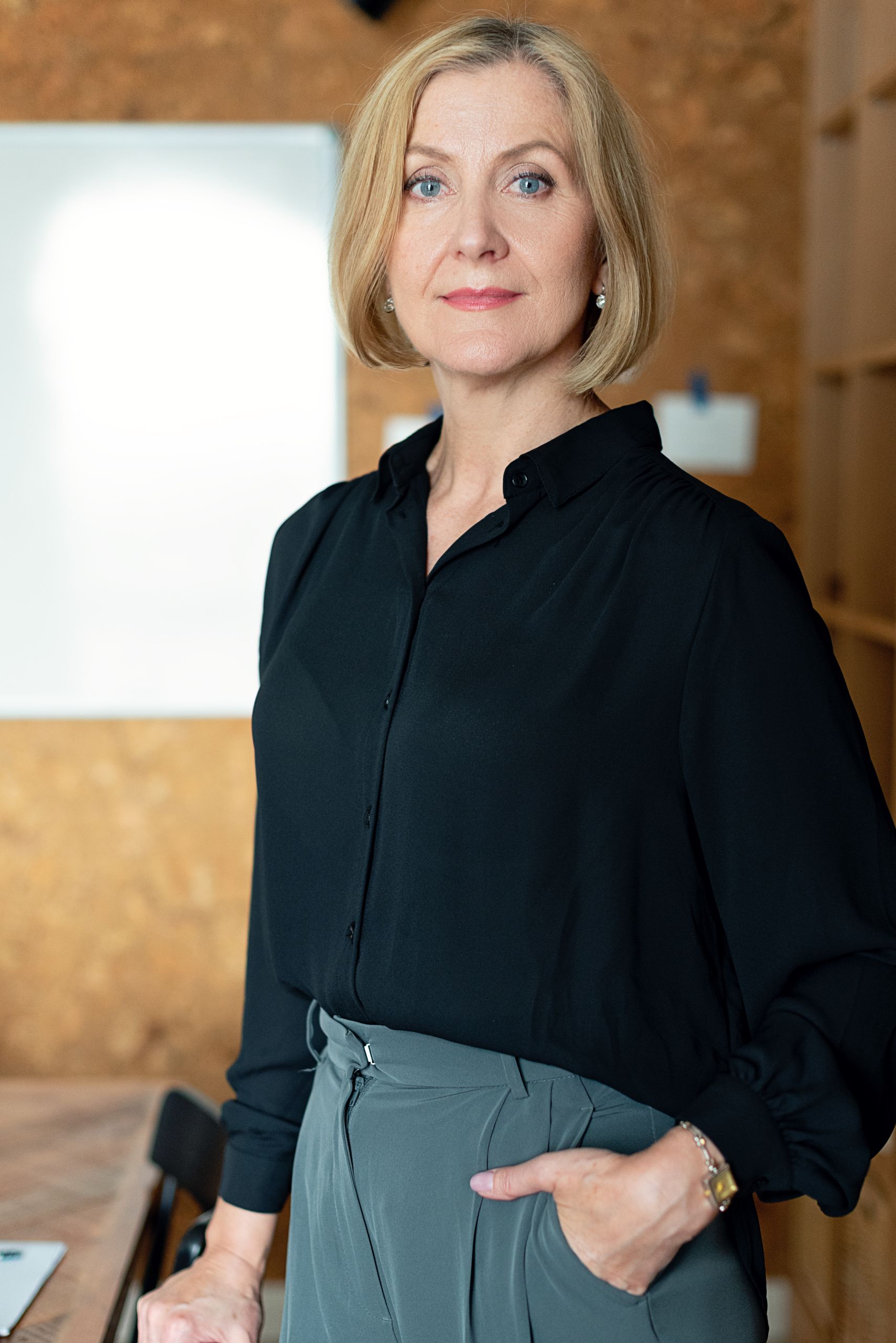 Confident mature businesswoman in office attire posing confidently indoors.